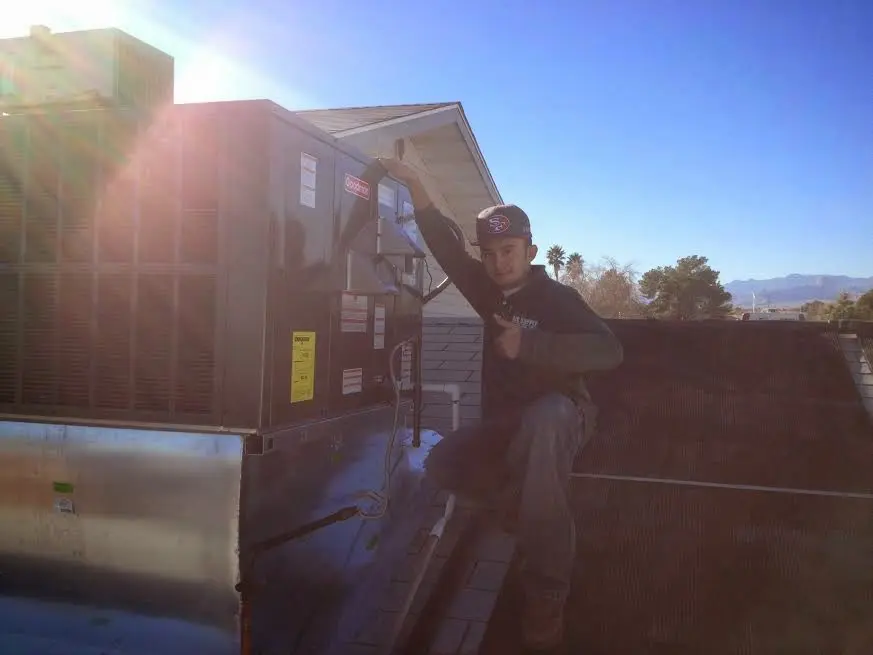 HVAC technician performing AC Tune-Up on a rooftop unit in Bloomfield
